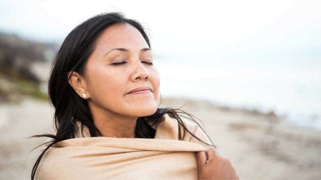 Woman at beach enjoying the sun on her face with her eyes closed