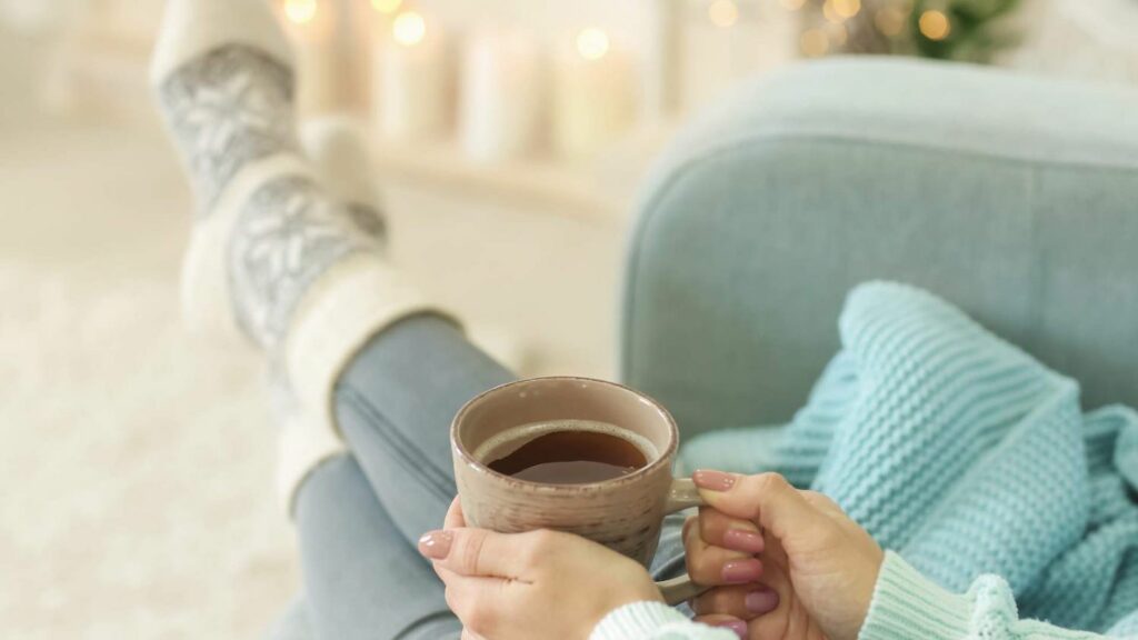 woman sitting on comfy chair with coffee and wool socks